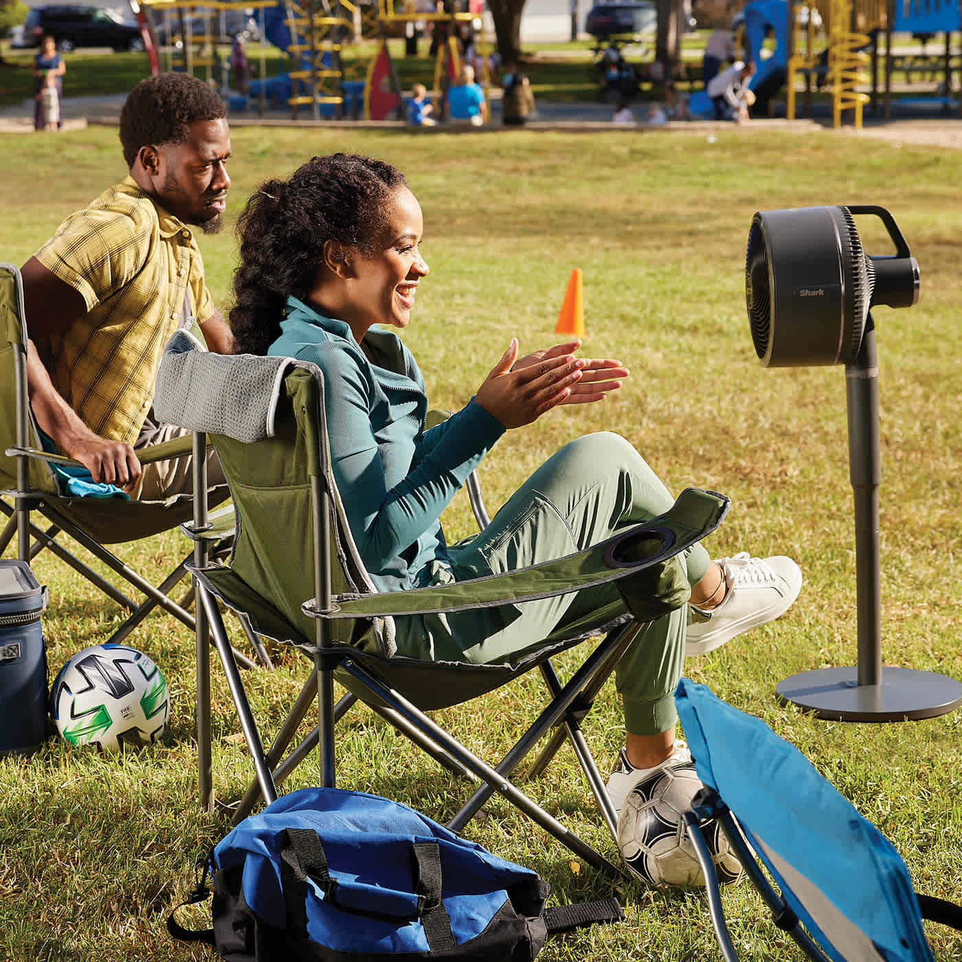 Image of man and woman sat at the park with the Shark FlexBreeze fan