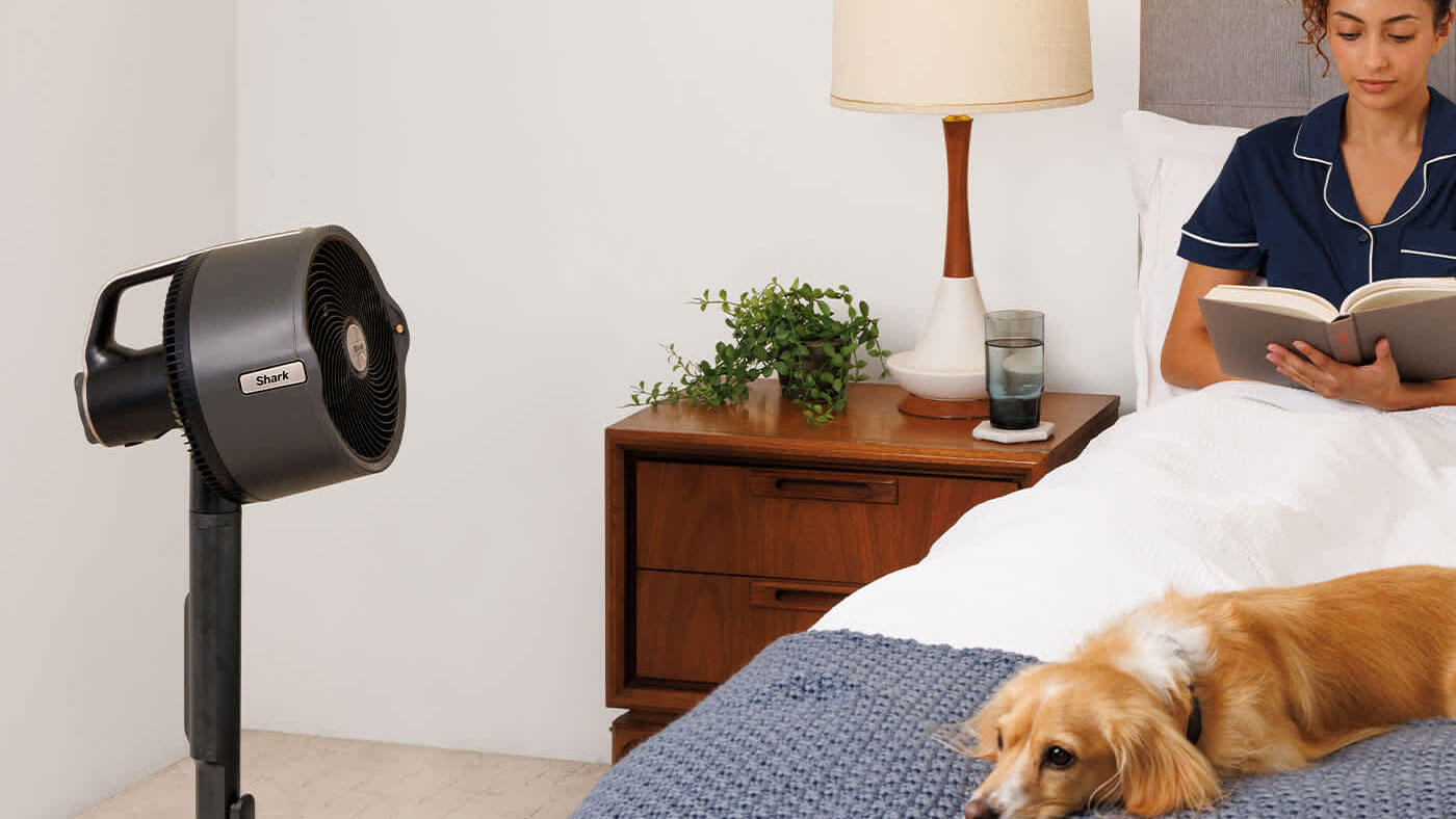 Image of Woman sat reading a book on her bed with the Shark fan