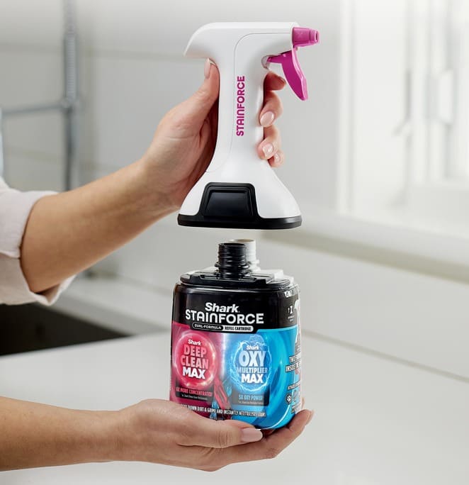 Hands attaching a Shark StainForce handheld sprayer to a Deep Clean Max and Oxy Multi-Purpose Max cleaning solution bottle.